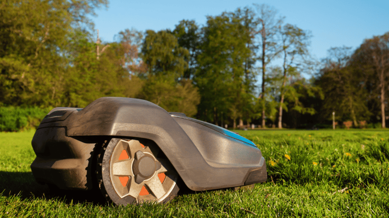 Robot lawn mower cutting grass in a lush garden setting.
