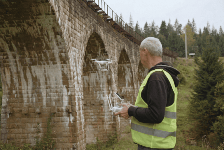 Drone operator conducting environmental monitoring near historic bridge.