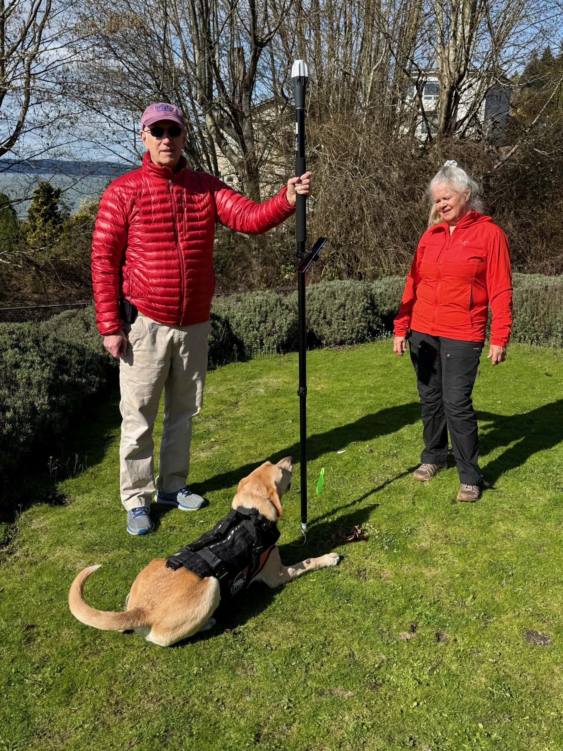 K9 detection handler with Emlid RX2 RTK receiver on survey pole and human remains detection dog in Washington State