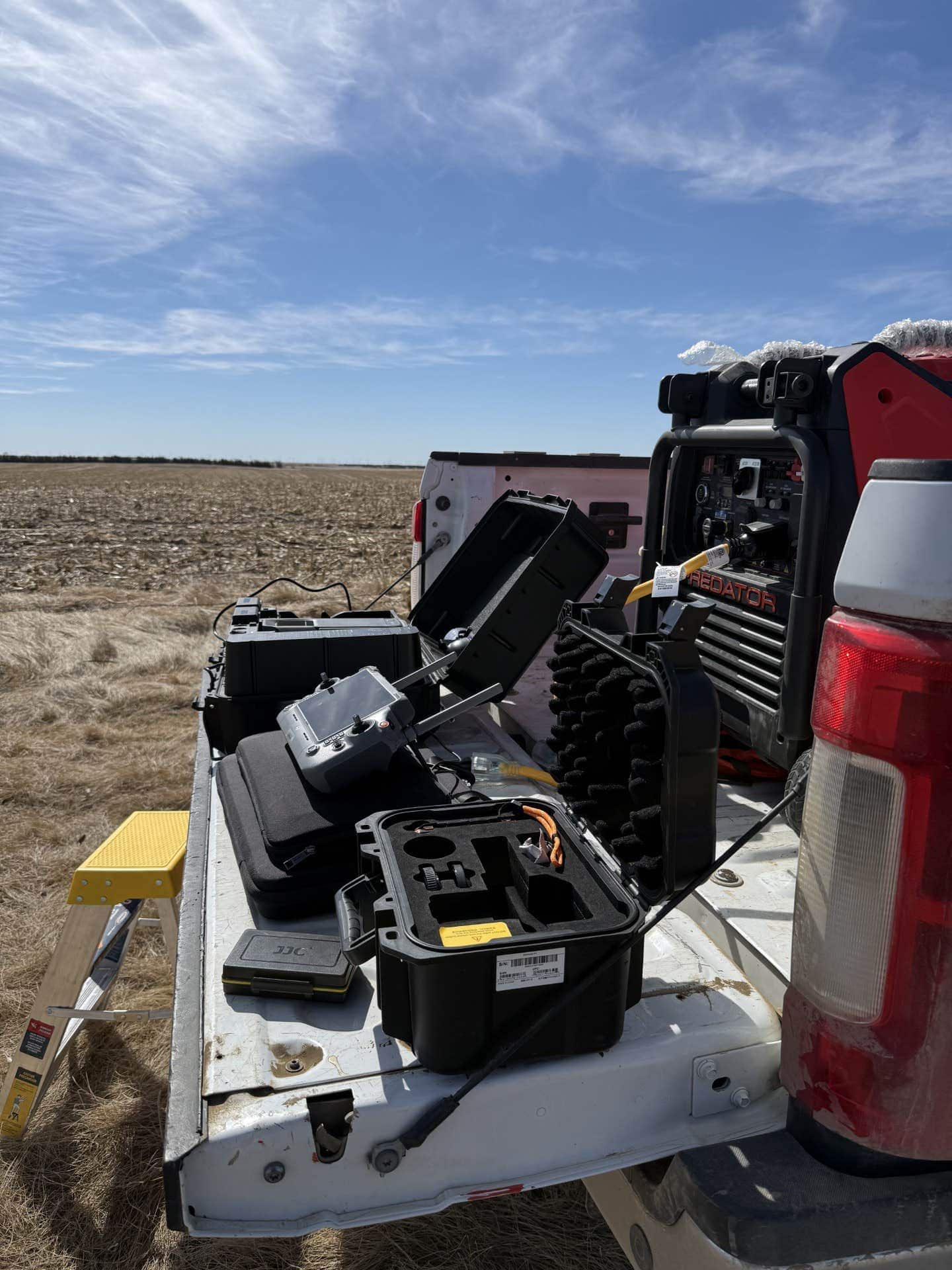 AeroAg Drone Services mobile office: truck tailgate set up as a field deployment station in South Dakota with DJI Matrice 400 controllers, drone case, and Predator generator, RTKdata NTRIP corrections delivered over Starlink uplink