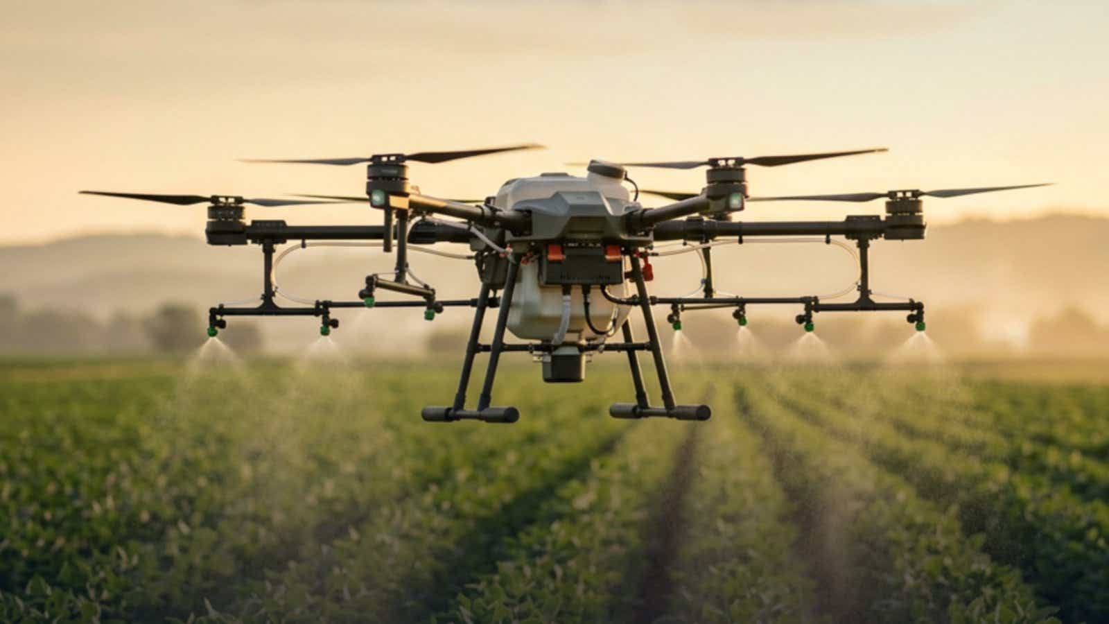 Spray drone with extended boom arms releasing product over crop rows at dusk